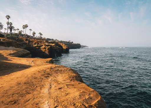 Adaptive swim lessons in San Diego beach at sunset with a lifeguard tower and ocean waves, representing ClearHaven Swim service area
